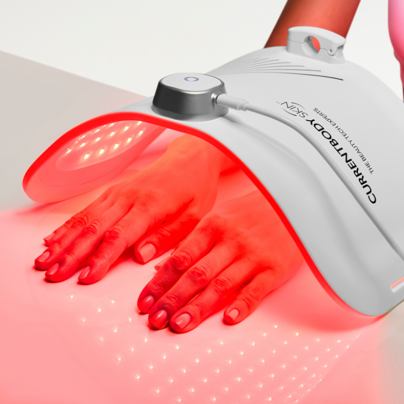 Hand in an LED light therapy panel for age spot removal